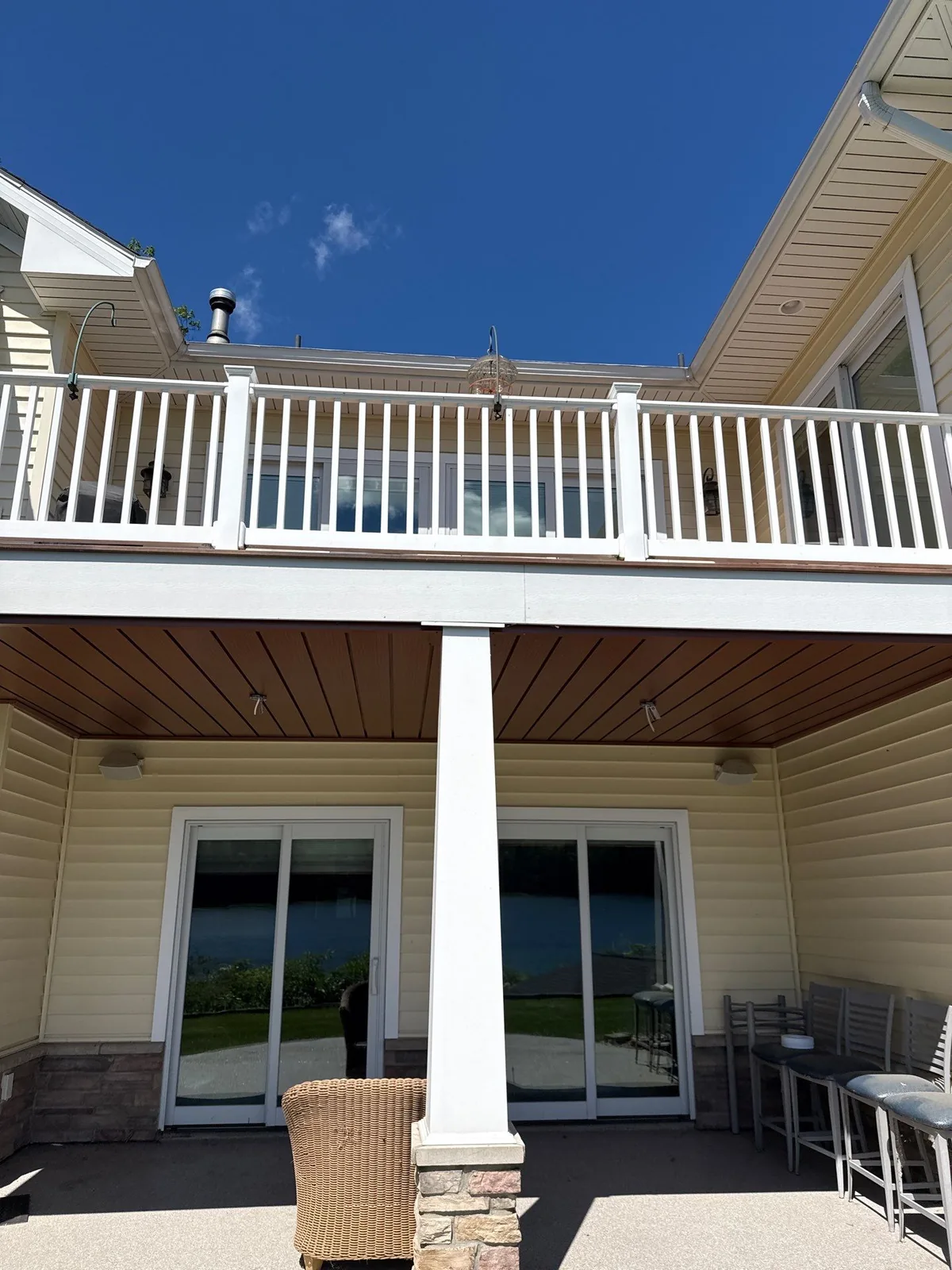 Brown under-deck ceiling above a patio with seating, white posts and sliding glass doors
