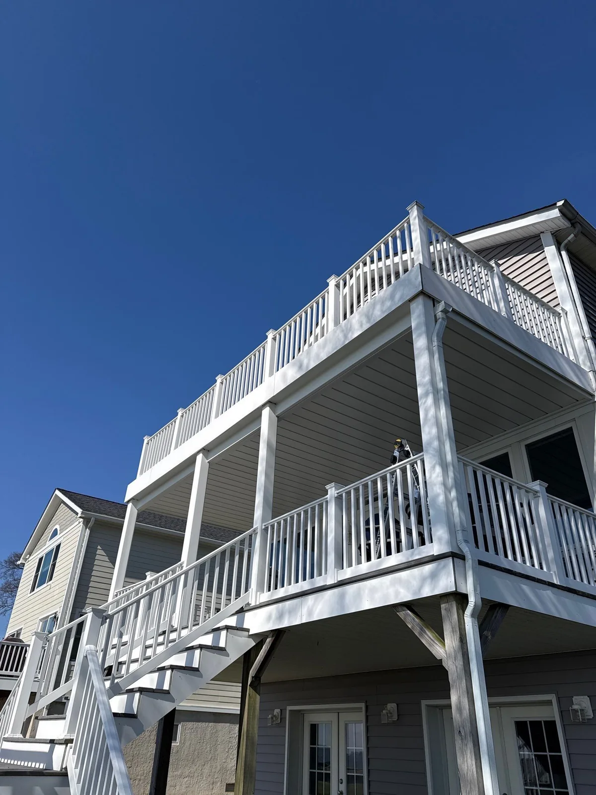 Finished light-colored under-deck ceiling above an elevated outdoor living area with white railings