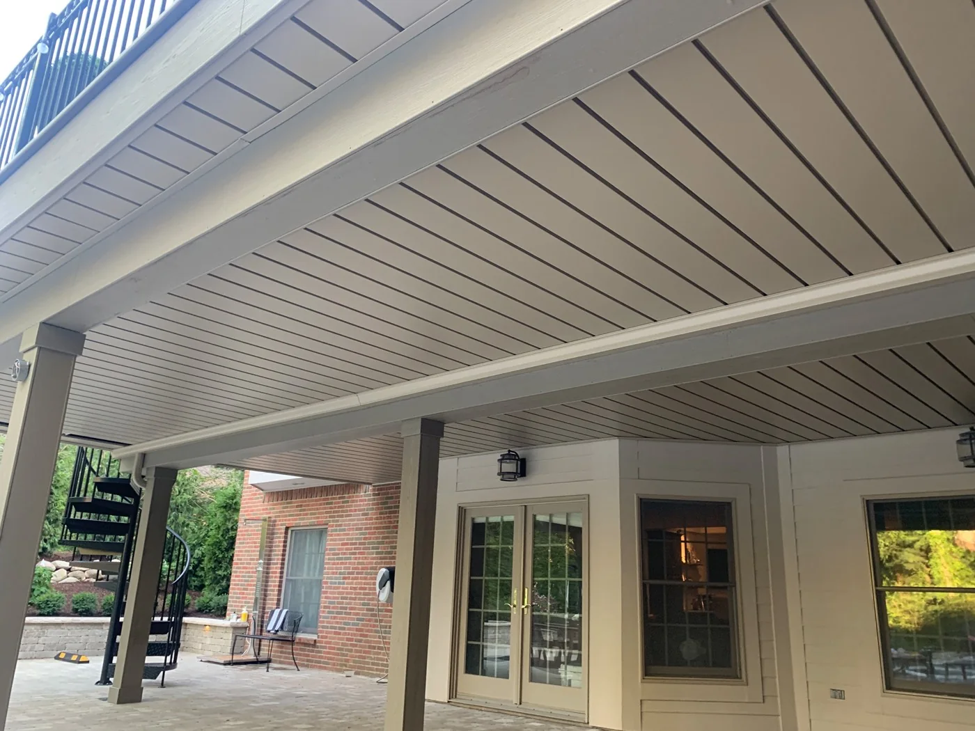 Close view of interlocking white aluminum ceiling panels beneath a deck